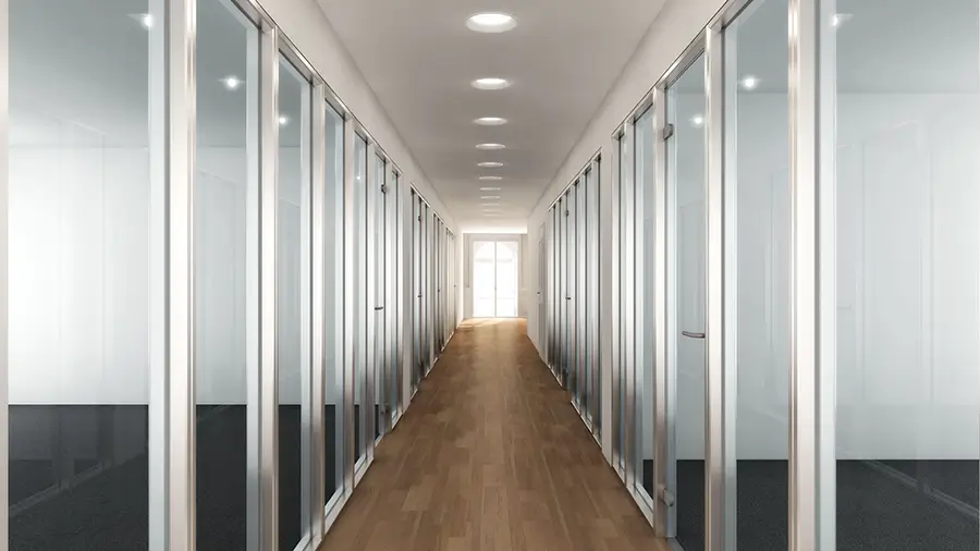 Office with a well lit hallway leading to an entrance door in the distance