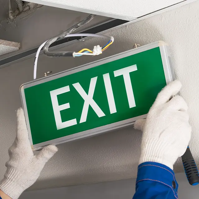 Worker completes installation of lighting signs emergency exit