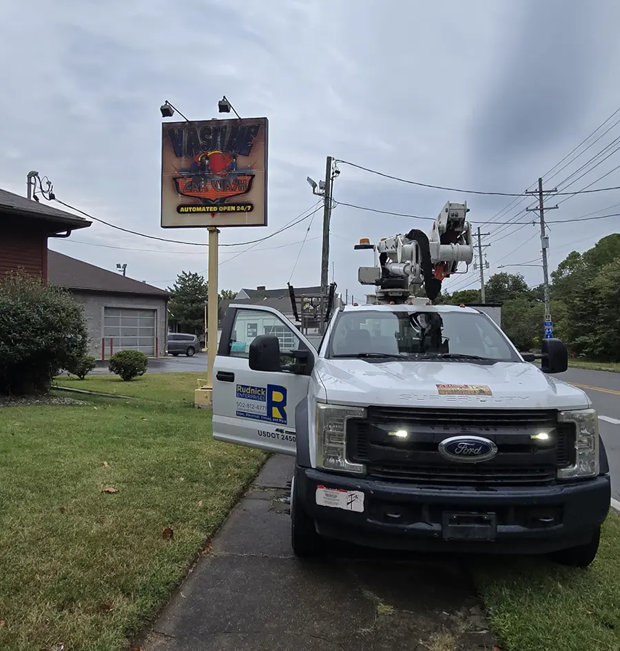 Rudnick Enterprises truck pulled up on sidewalk to inspect a sign in need of repair