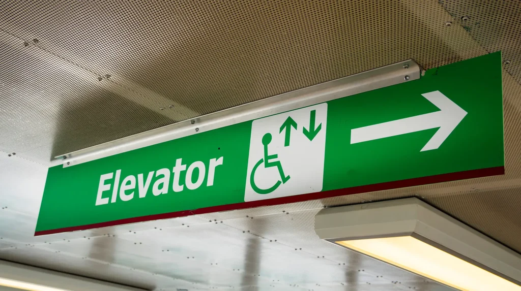 ADA wayfinding signage pointing out the location of a handicapped accessible elevator