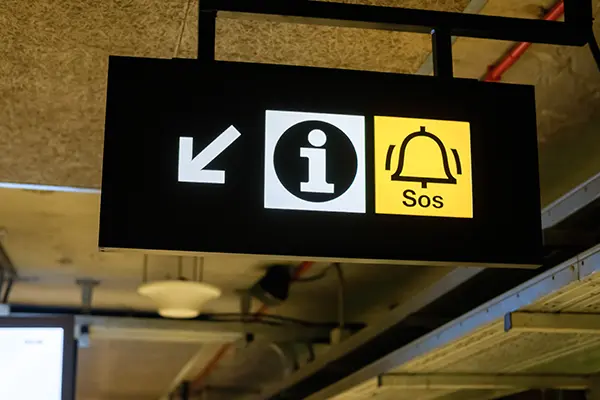 Overhead wayfinding sign with simple graphic icons depicting information and alarm locations