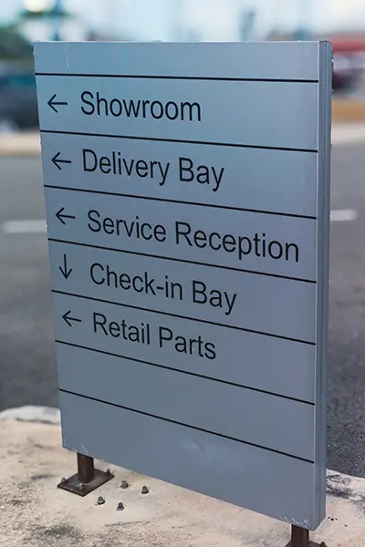 Parking lot sign with direction to various parts of a service facility